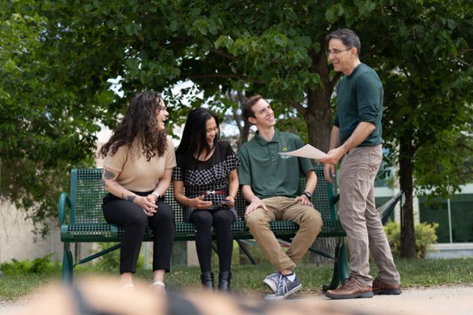 Students sitting outside on a bench.