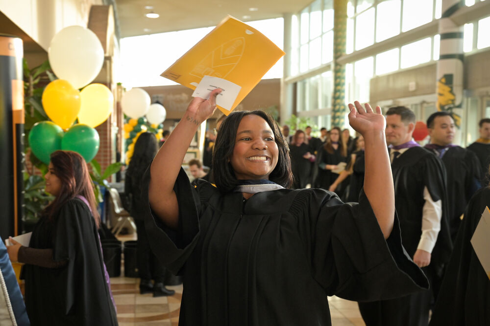 A student raising their hands in happiness at convocation