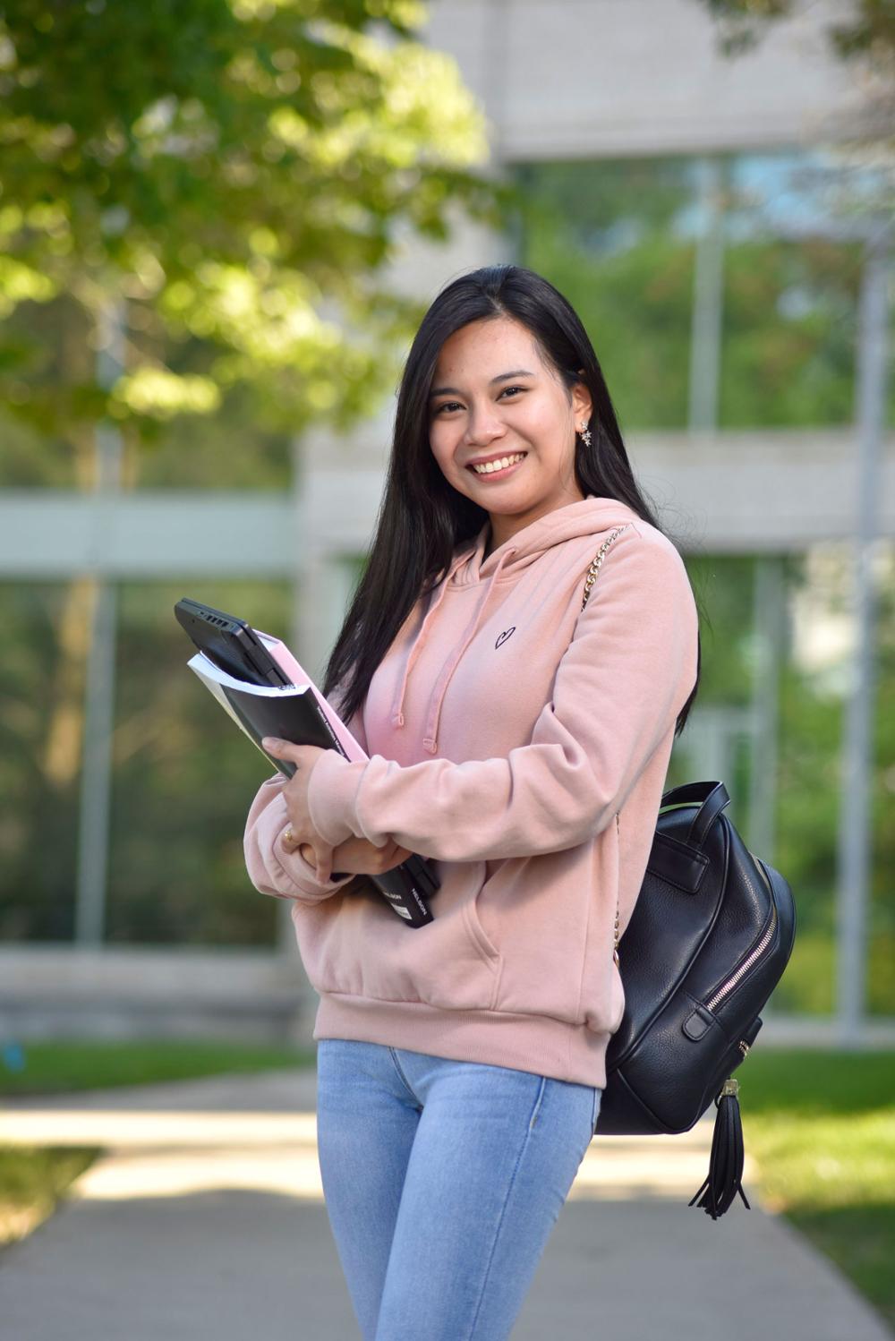 Student standing holding books outside on campus