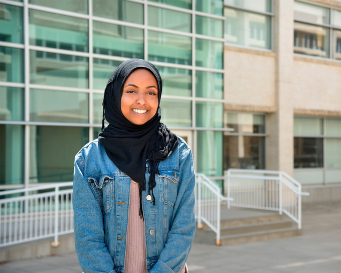 Student poses at a wall on campus
