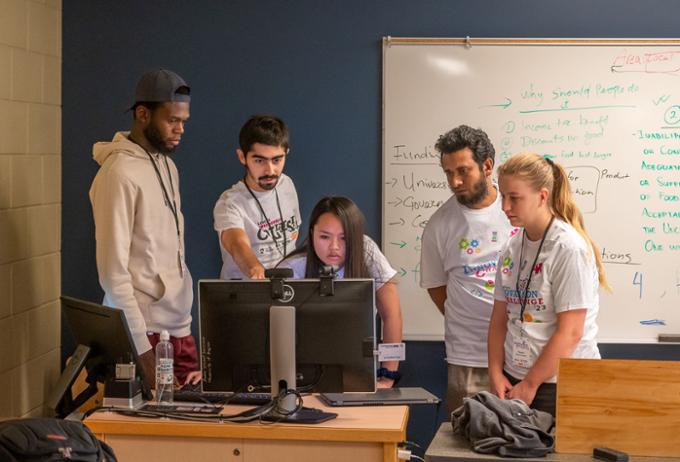 Team 2 gathers around a computer in their room.