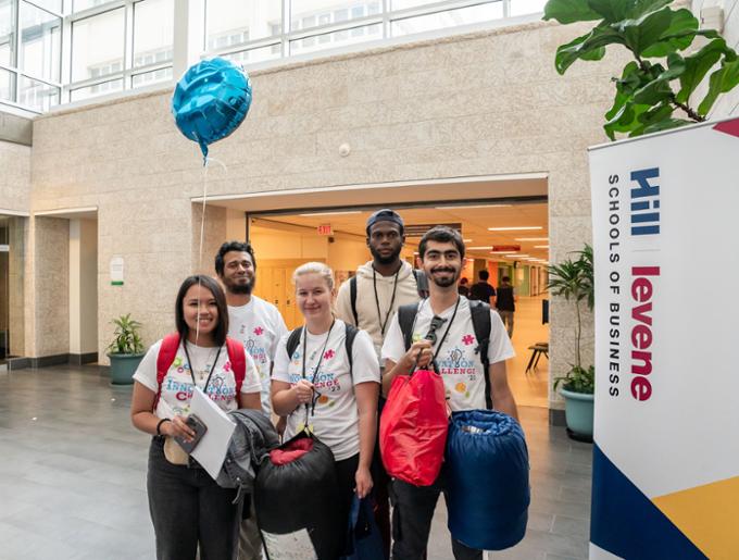 Team 2 poses with their bags, sleeping bags, and balloon outside of the presentation room.