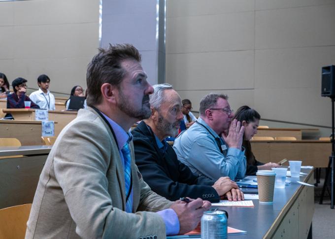 Four judges are sitting in the front row. From left to right: Peter Moroz, Mark Borgares, Brett Waytuck, and Evelyn Cerda.