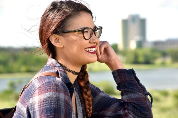 Student sitting in the park, smiling and looking off-camera