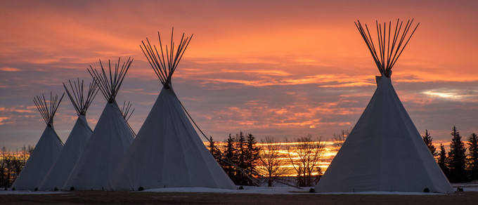 Five tipis with a sunset in the background