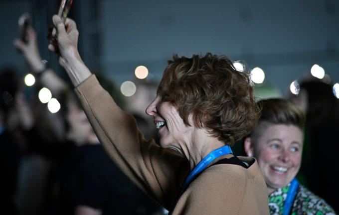 Two women hold up their phones like candles