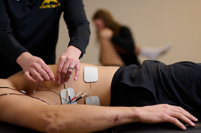 Athletic Therapist placing electrodes to patients abdomen