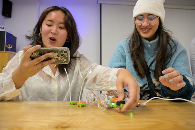 Two students using gadgets and circuits