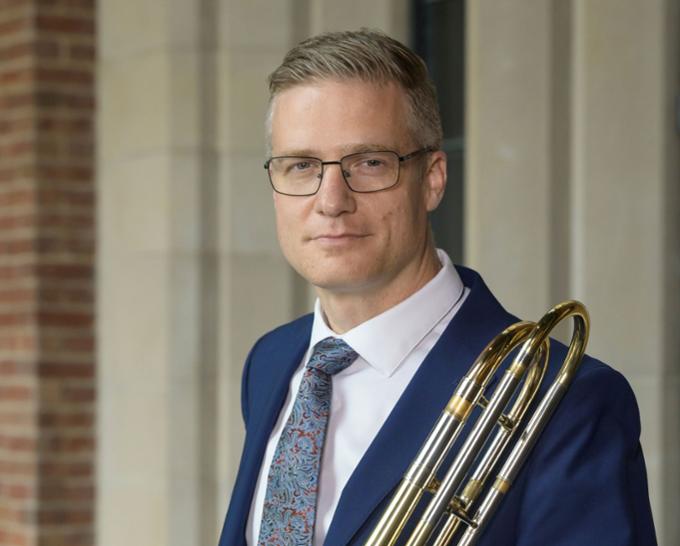 A man standing with a trombone