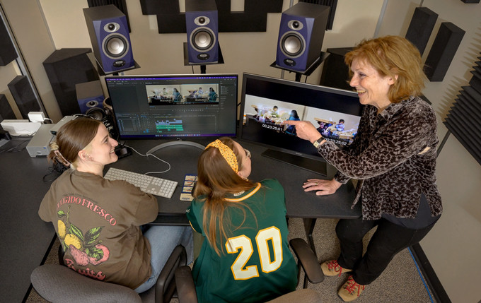 three people in a video editing suite