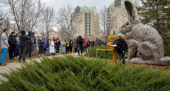 a group of people surround a rabbit sculpture