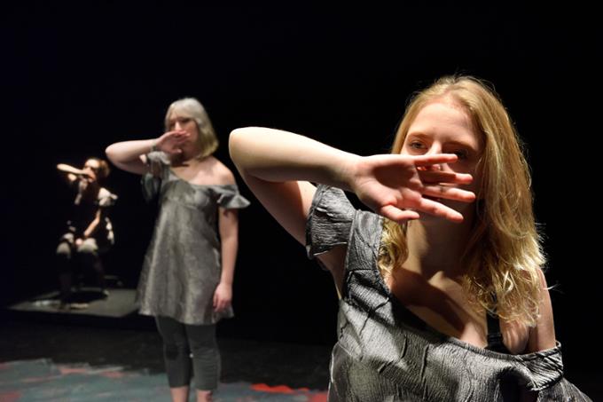 Three students on stage performing a play