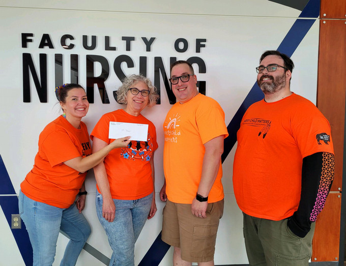 4 team members standing in front of the Faculty of Nursing office.