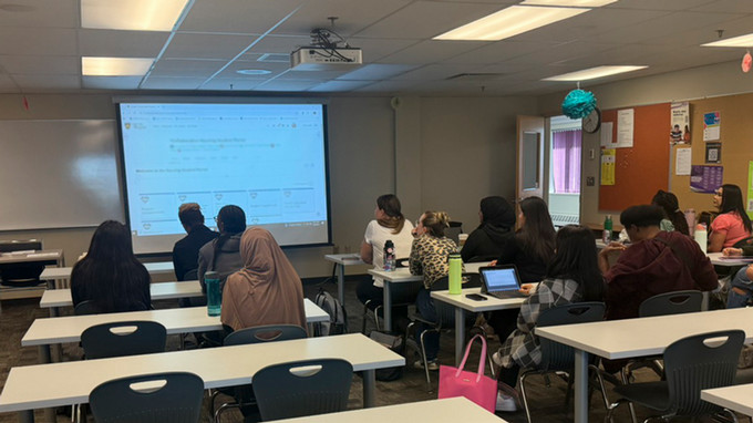 attentive nursing students sitting at desks watching a presentation