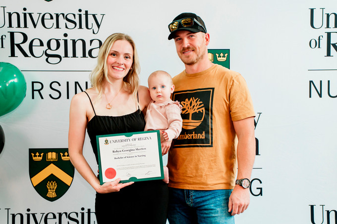 a recent RN graduate holding her degree and baby girl posing for a picture with her husband