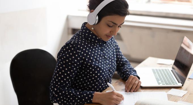 woman with headphones working at a laptop