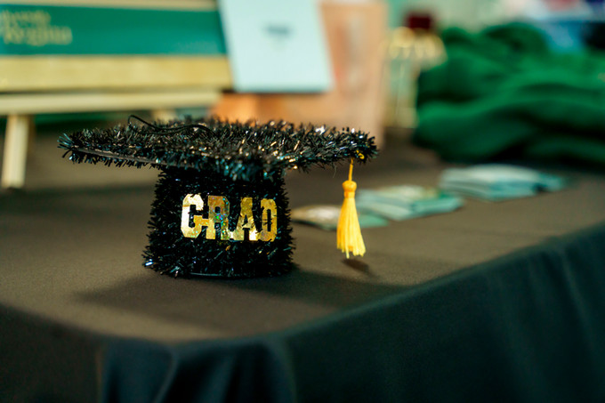a decorated table with a black tinseled graduation hat with grad in gold lettering