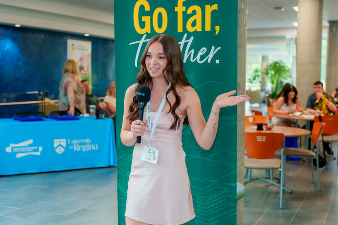 candid photo of female nursing grad holding a microphone and giving a message to camera
