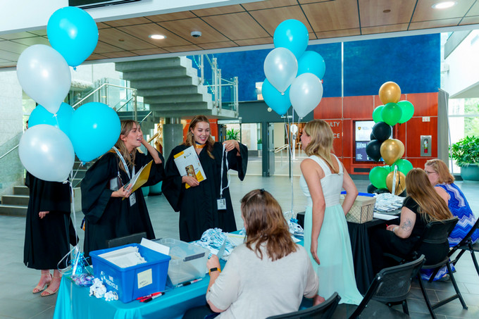 group photo of 2 female nursing graduates picking up their name tag for the convocation after event