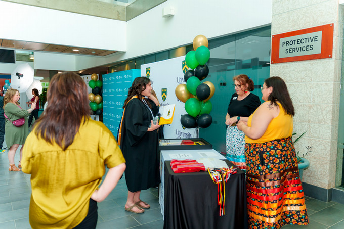 candid photo of an indigenous female nursing graduate speaking with two indigenous female staff members