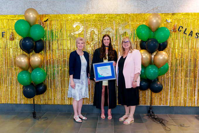 group photo of a female nursing graduate holding award with 2 female deans of either side 