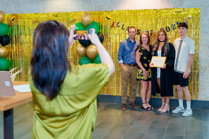 candid photo of a nursing grad and her family being photographed