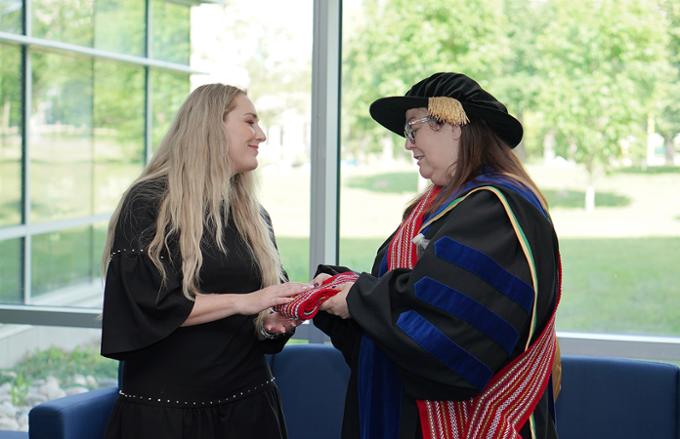 nursing dean presenting metis sash to graduate