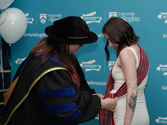 nursing dean pinning metis sash on graduat