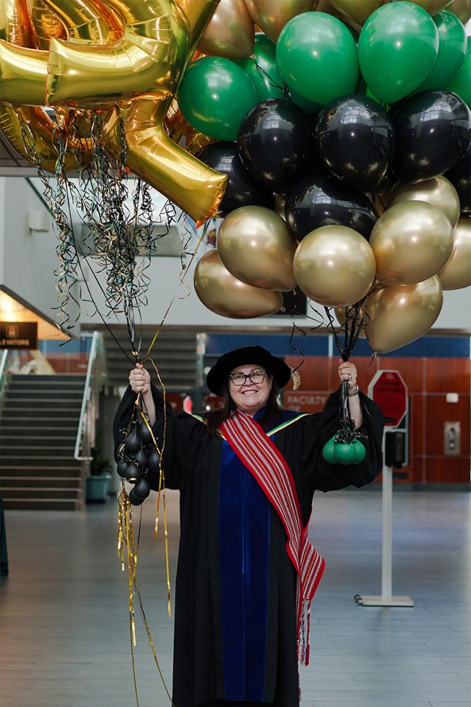 nursing dean holding graduation balloon boquets