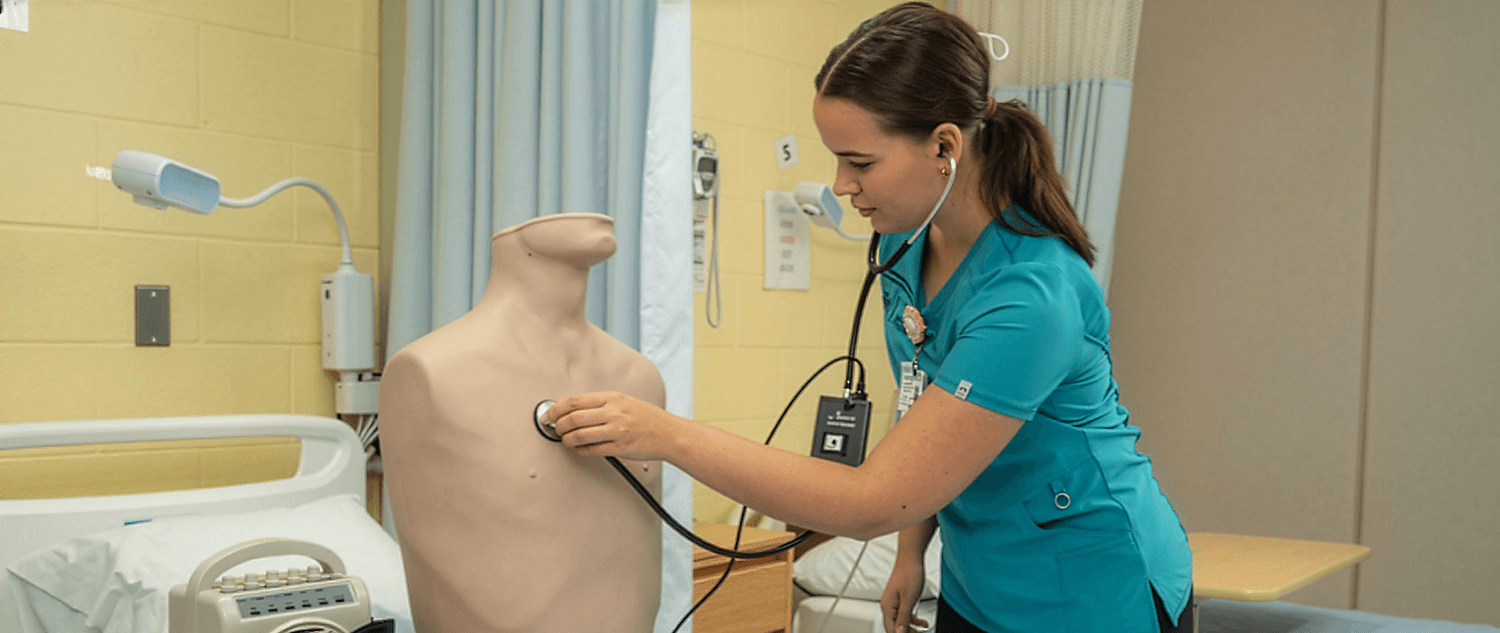 nursing student using a stethoscope in the simulation lab