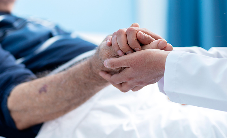 A doctor and elderly patient holding hands