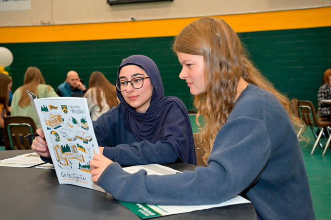 two people sitting and looking at a book