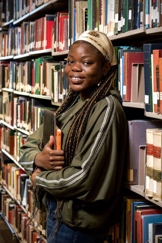 student holding books in library