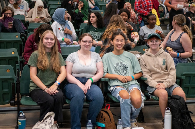 four people sitting on bleachers and smiling in a gymnasium