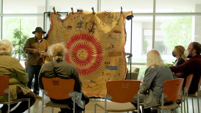 Elder giving a talk about a buffalo count painting on a buffalo hide