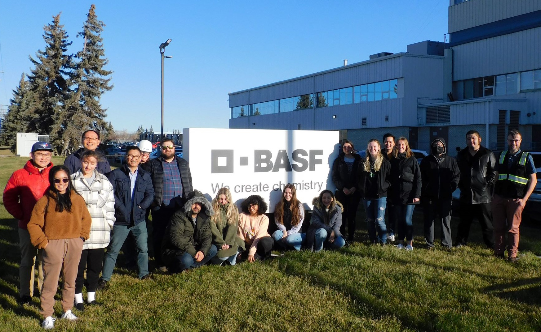 Chemistry students and professors standing in front of the BASF sign. 