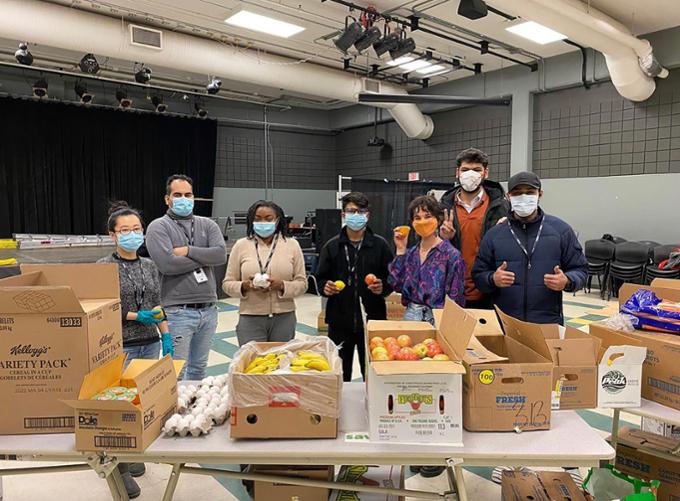 Seven students are posing for a photo as they organize food hampers.