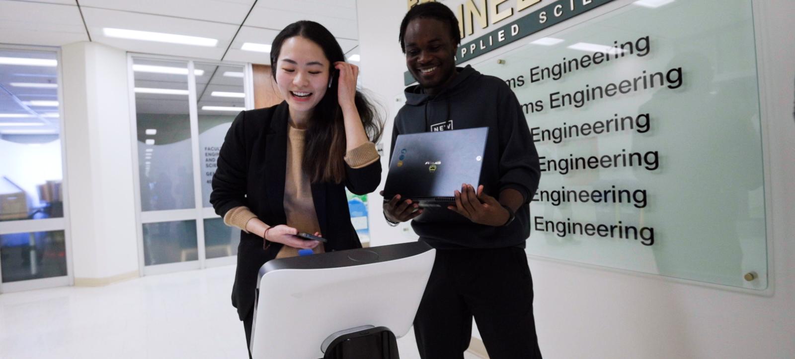 Two students having fun at an electronic kiosk.
