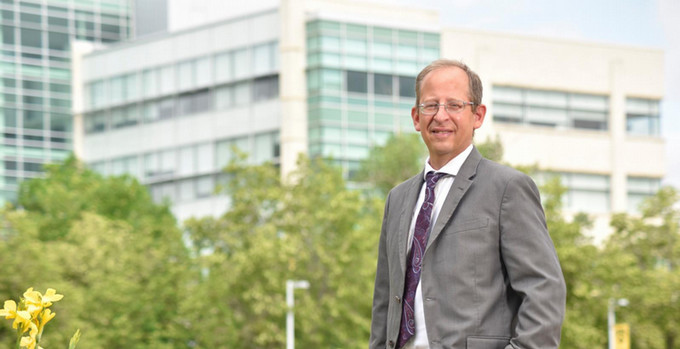 a smiling man outdoors on campus