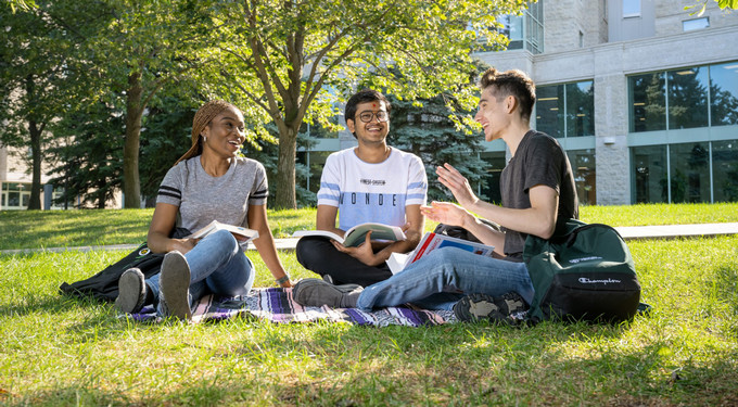 three students sitting outside on campus