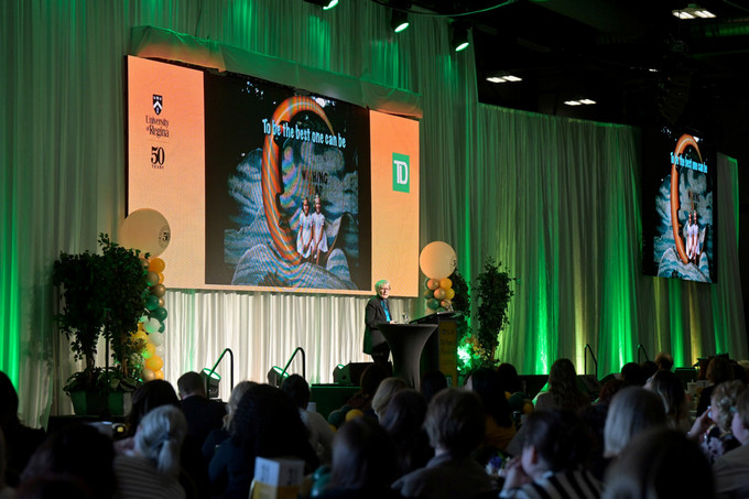 a large group of women listen to a speaker on a stage