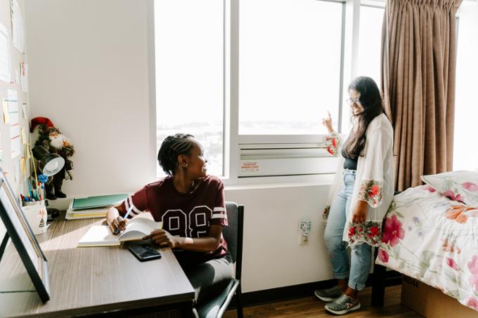 Two students talking in a dorm room.