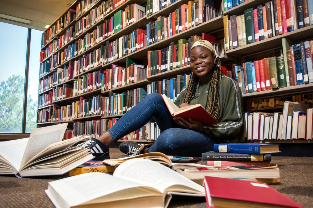 Student in the library posing with books