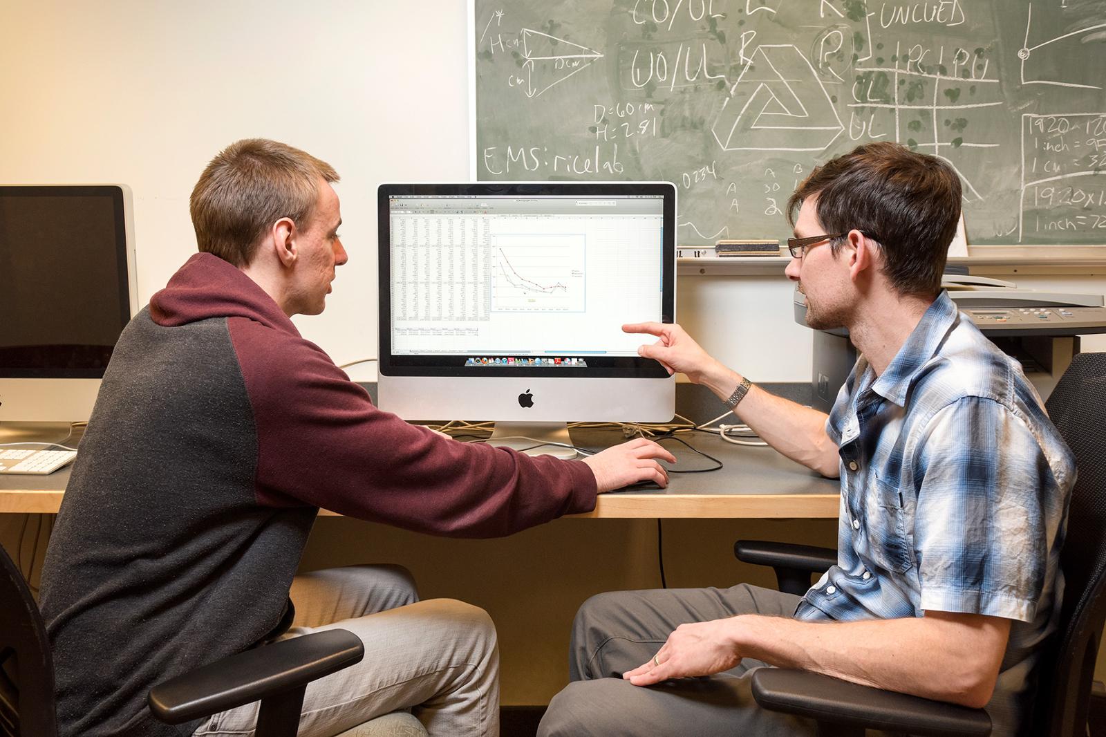 Two students are studying a computer program.