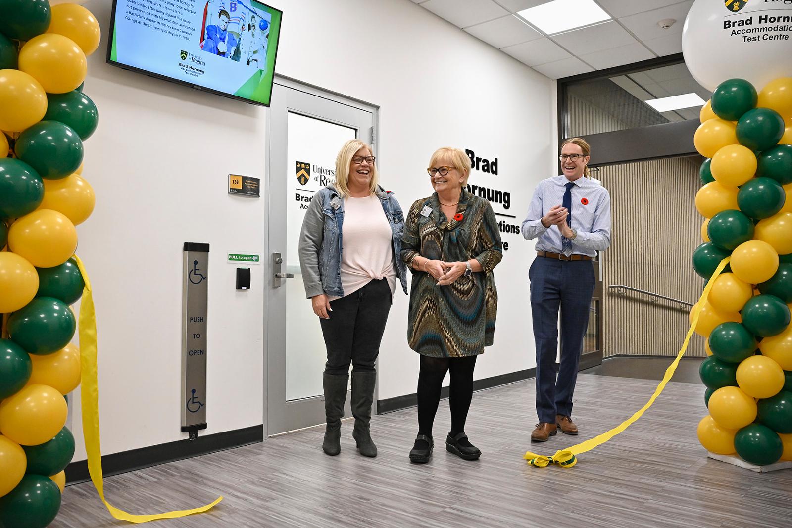 Three people are cutting a ribbon at an official opening ceremony for the Accommodations Test Centre