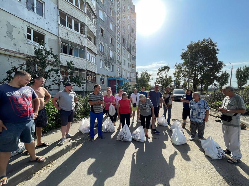 Group of people posing with plastic bags full of supplies.