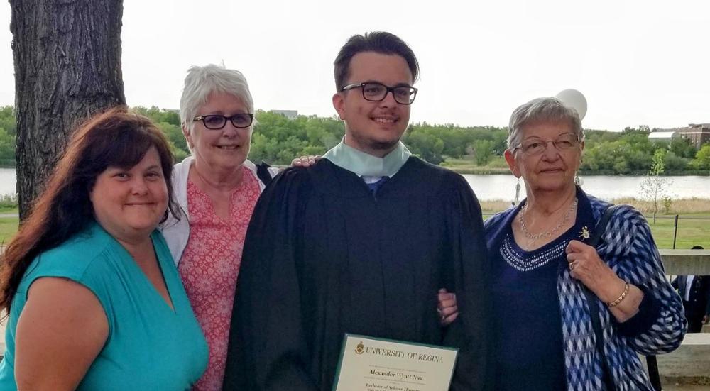 A man in convocation robes poses with his family.