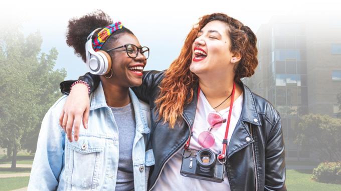 Two students walking across campus sharing a laugh among close friends.