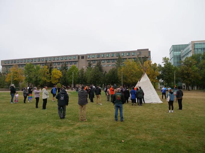 A view of the academic green, bustling with activity before the tipi raising event.
