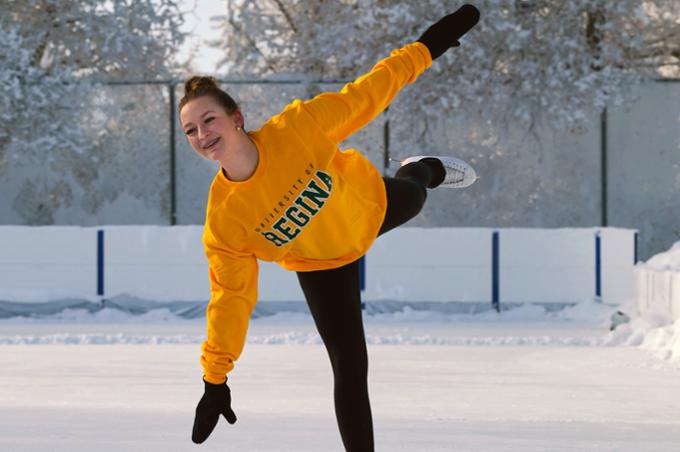 A young woman figure skating outside on a nice winter day.